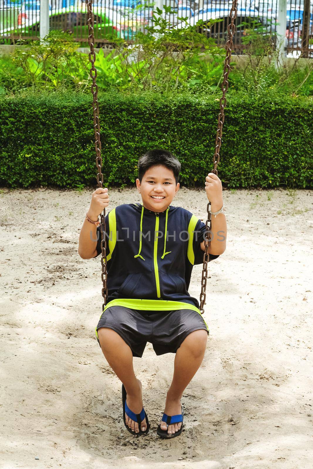 Happy asian sport boy play on swing playground in Garden