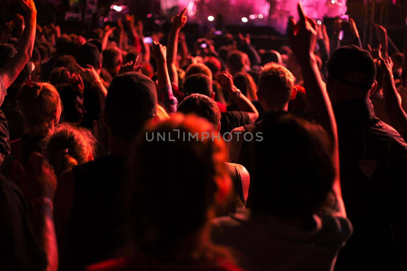 crowd of people with arms raised in the red light of lights