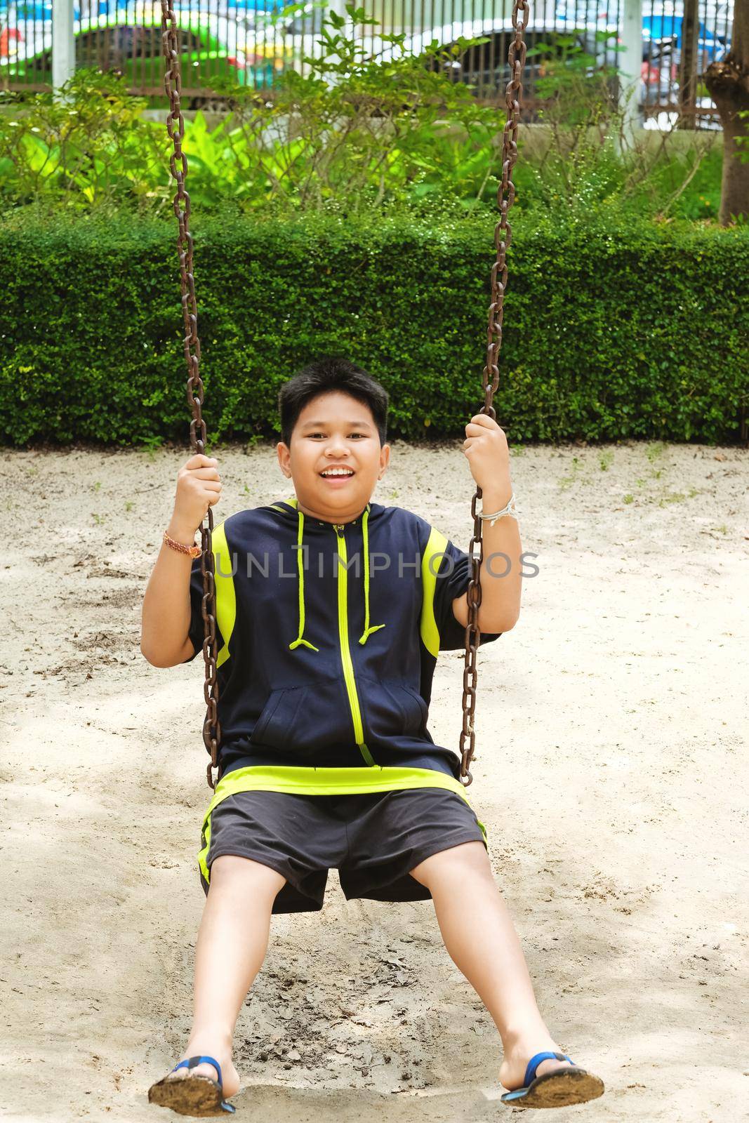 Happy asian sport boy play on swing playground in Garden. by Benzoix