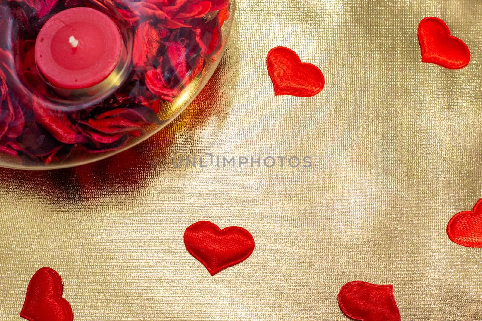 red candle in a candlestick on a golden background with red hearts, copy space