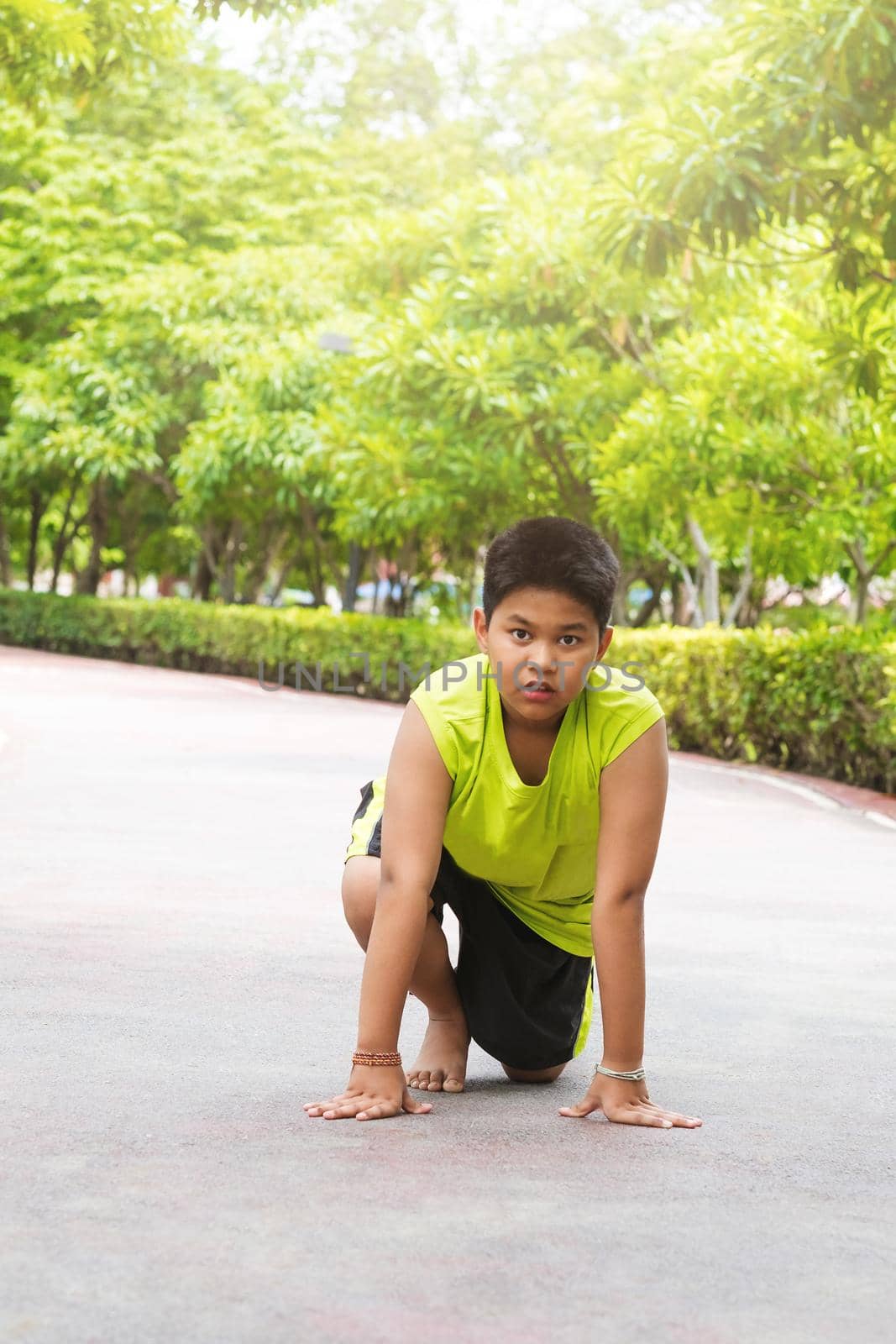 Young Asian boy prepare to start running on track in the garden during day time to practice himself