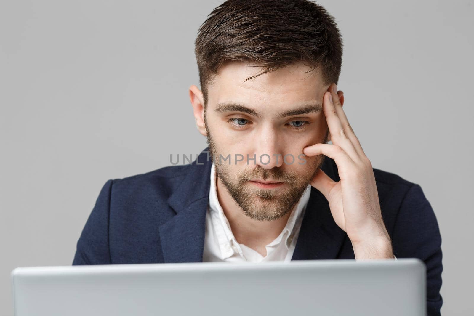 Business Concept - Portrait handsome serious business man in suit looking at laptop. White Background. by Benzoix