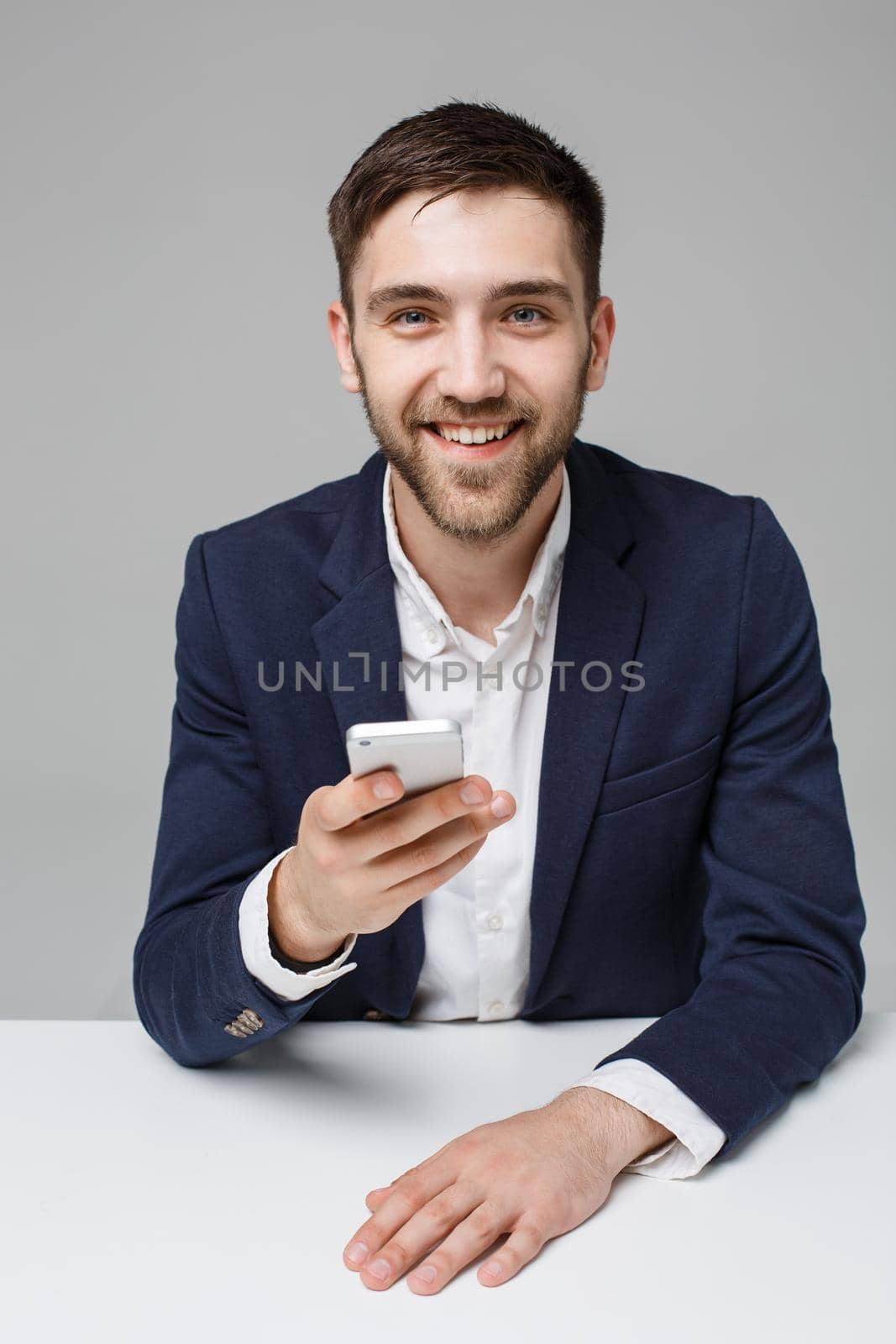 Business Concept - Portrait handsome happy handsome business man in suit playing moblie phone and smiling with laptop at work office. White Background.