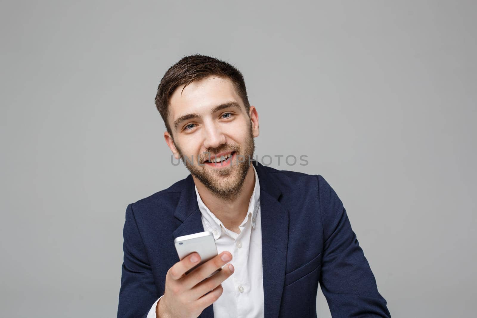 Business Concept - Portrait handsome happy handsome business man in suit playing moblie phone and smiling with laptop at work office. White Background. by Benzoix