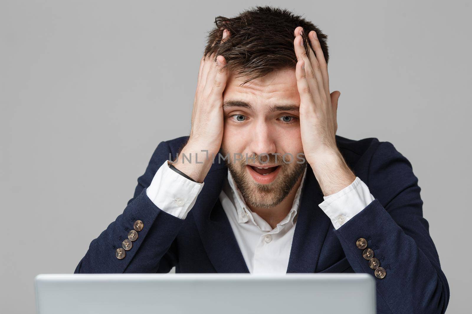 Business Concept - Portrait handsome stressful business man in suit shock looking at work in laptop. White Background. by Benzoix