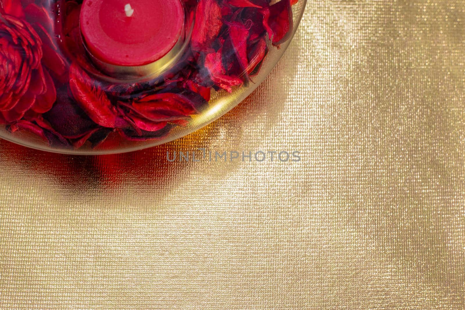 red candle in a candlestick on a golden background, copy space