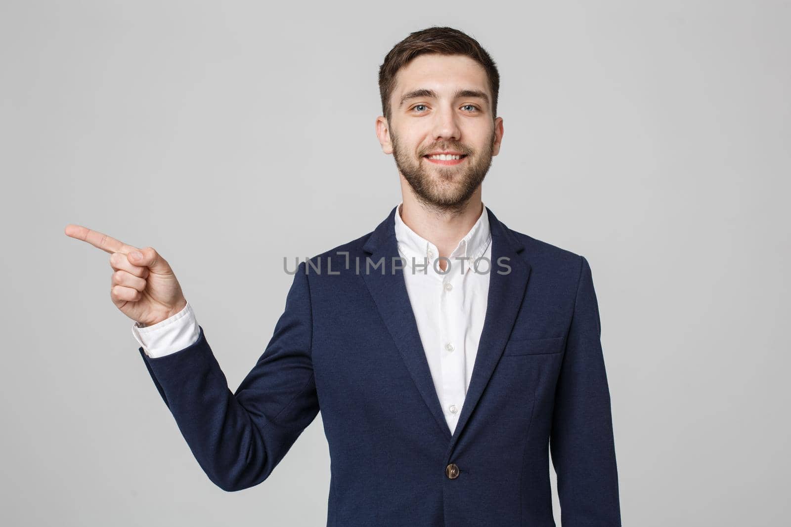 Young successful businessman pointing direction with finger over dark grey background. Copy space.