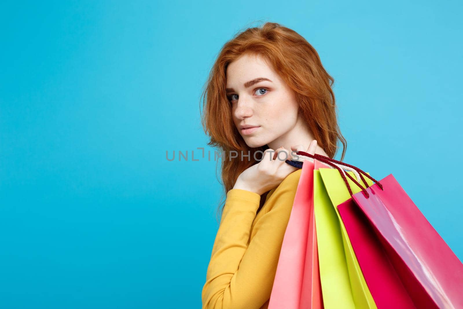 Shopping Concept - Close up Portrait young beautiful attractive redhair girl looking at camera. Blue Pastel Background. Copy space.