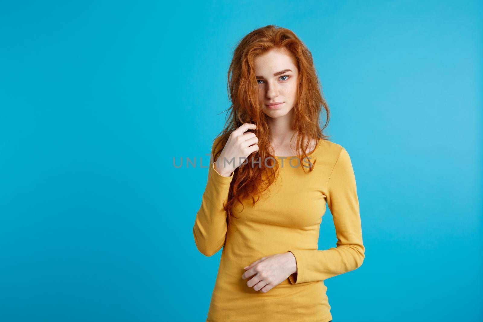 Portrait of young beautiful ginger woman confident looking at camera. Isolated on pastel blue background. Copy space.