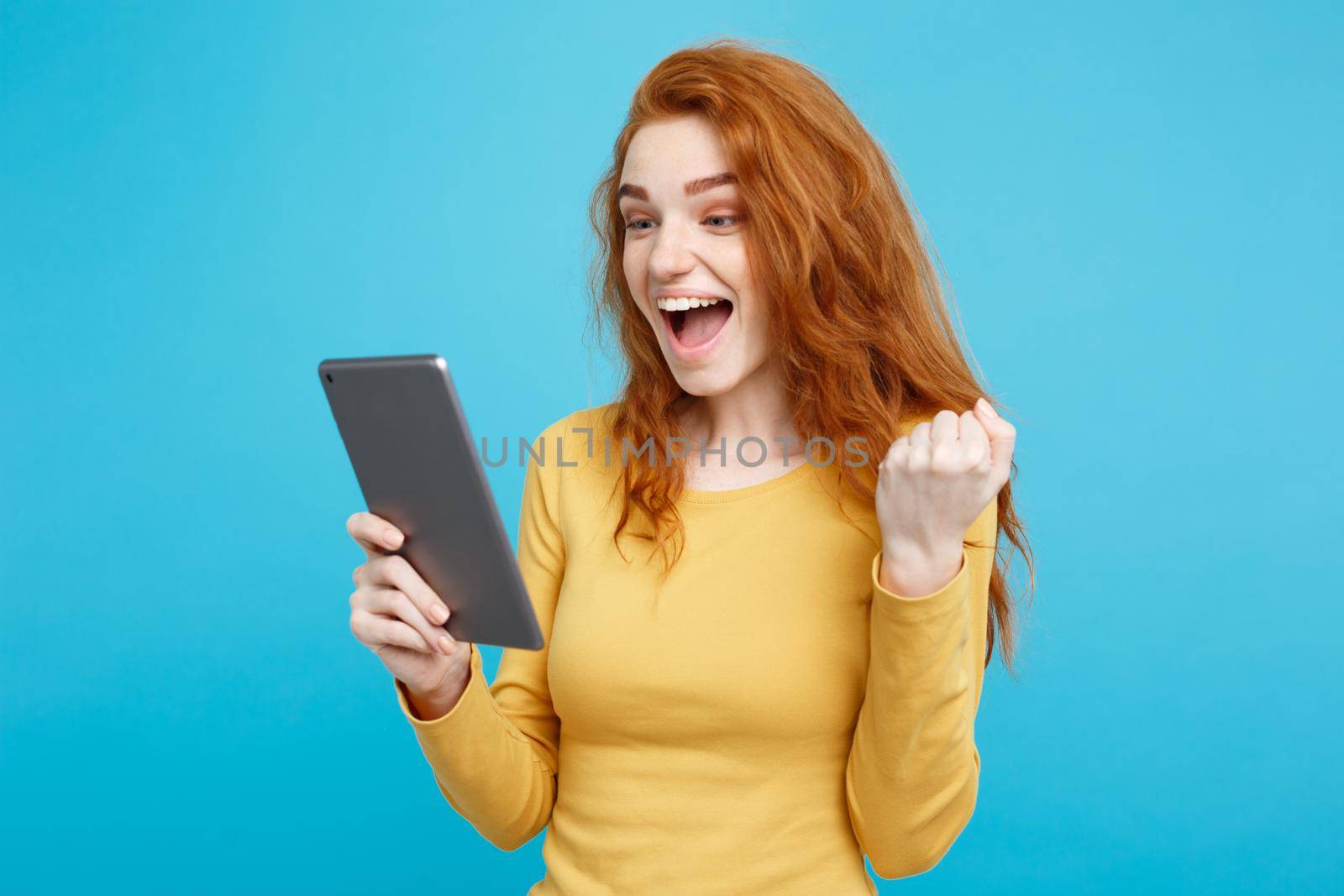 Close up Portrait young beautiful attractive redhair girl happy smiling on digital table with wining something. Blue Pastel Background. Copy space.