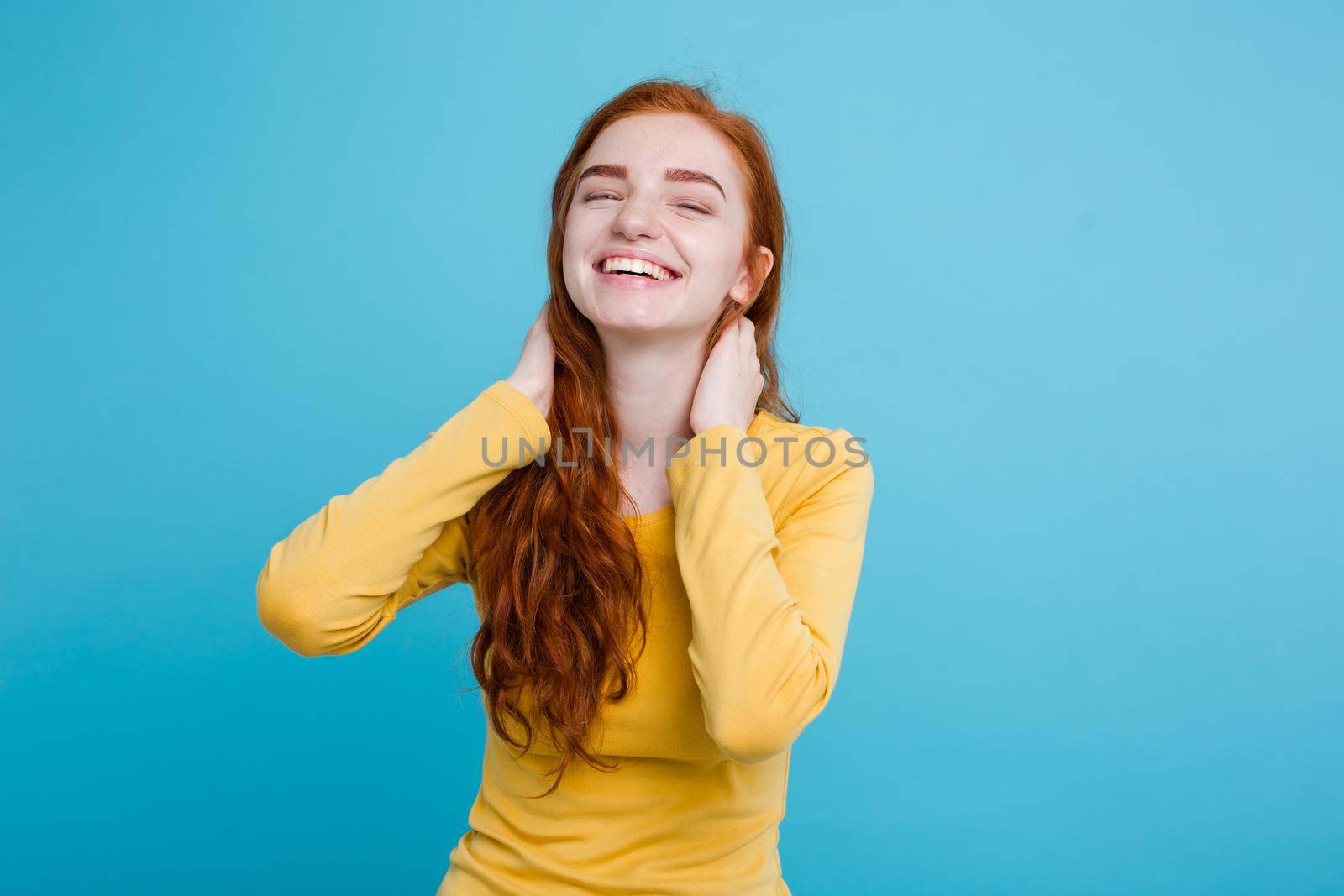 Portrait of happy ginger red hair girl with freckles smiling looking at camera. Pastel blue background. Copy Space by Benzoix