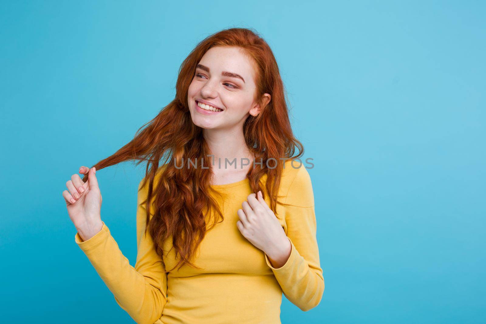 Portrait of happy ginger red hair girl with freckles smiling looking at camera. Pastel blue background. Copy Space by Benzoix