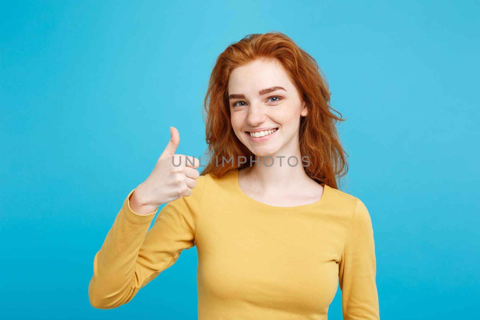 Portrait of young stylish freckled girl laughing with showing thumps up at camera. Copy space. by Benzoix