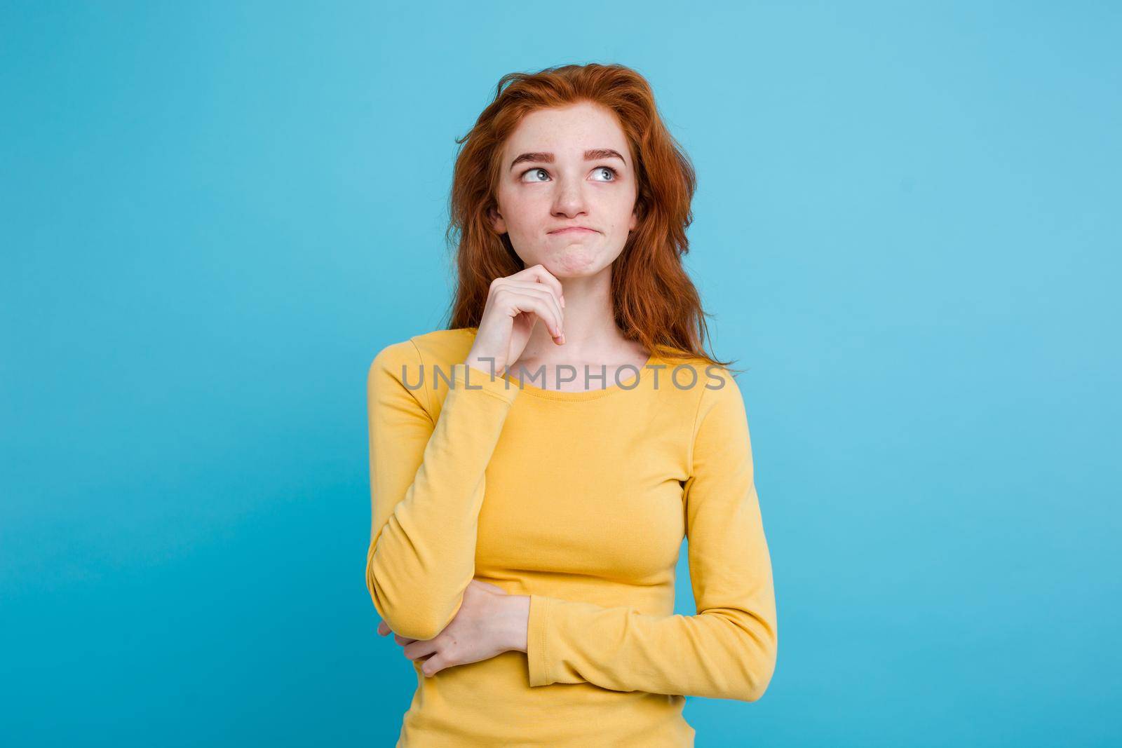 Portrait of happy ginger red hair girl with freckles smiling looking at camera. Pastel blue background. Copy Space by Benzoix