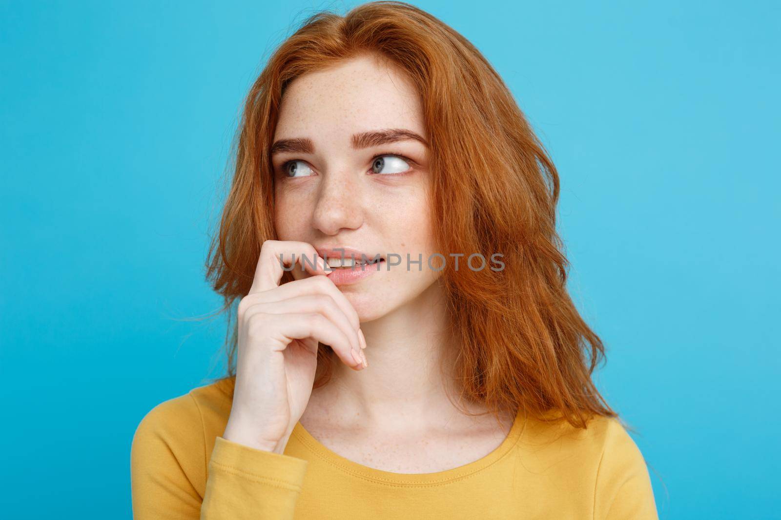 Headshot Portrait of happy ginger red hair girl with freckles smiling looking at camera. Pastel blue background. Copy Space. by Benzoix