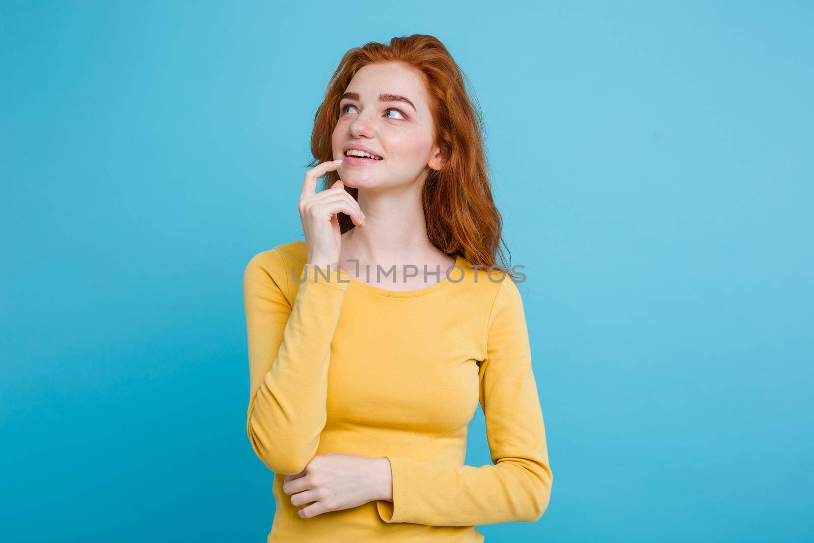 Portrait of happy ginger red hair girl with freckles smiling looking at camera. Pastel blue background. Copy Space by Benzoix