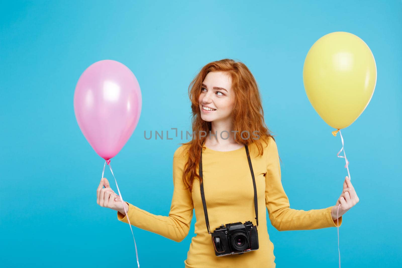 Lifestyle and Party concept - Close up Portrait young beautiful attractive ginger red hair girl with colorful balloon and vintage camera. Blue Pastel Background. Copy space.