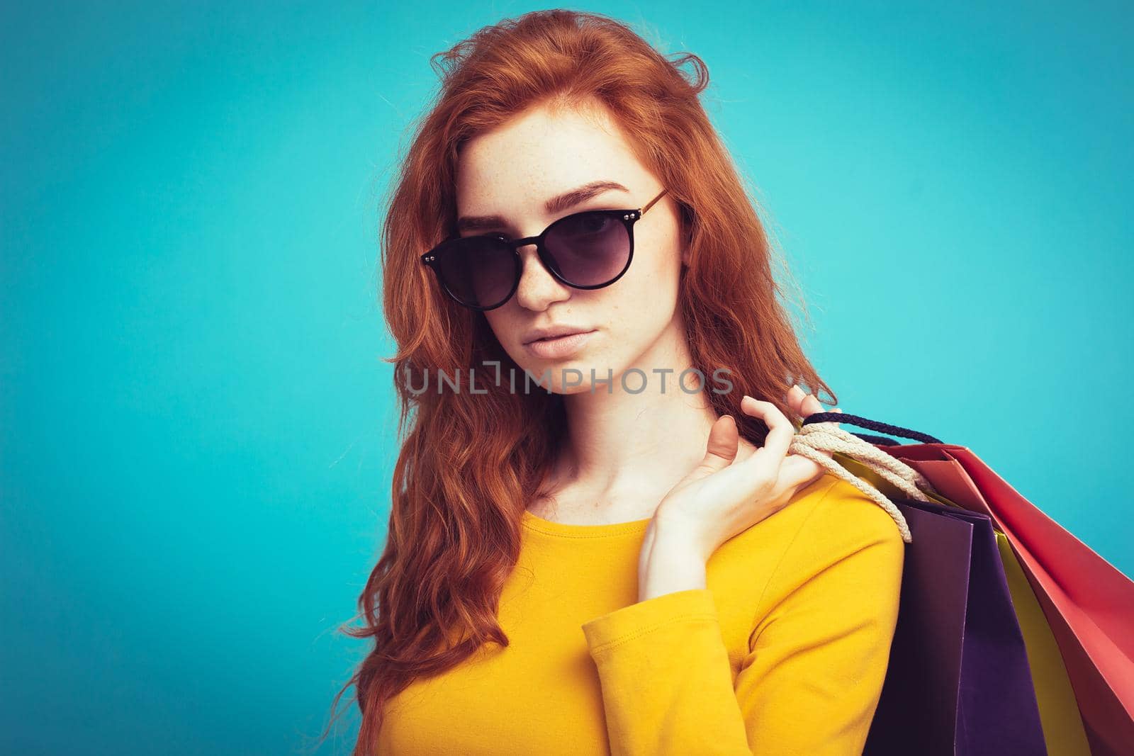 Shopping Concept - Close up Portrait young beautiful attractive redhair girl smiling looking at camera with shopping bag. Blue Pastel Background. Copy space by Benzoix