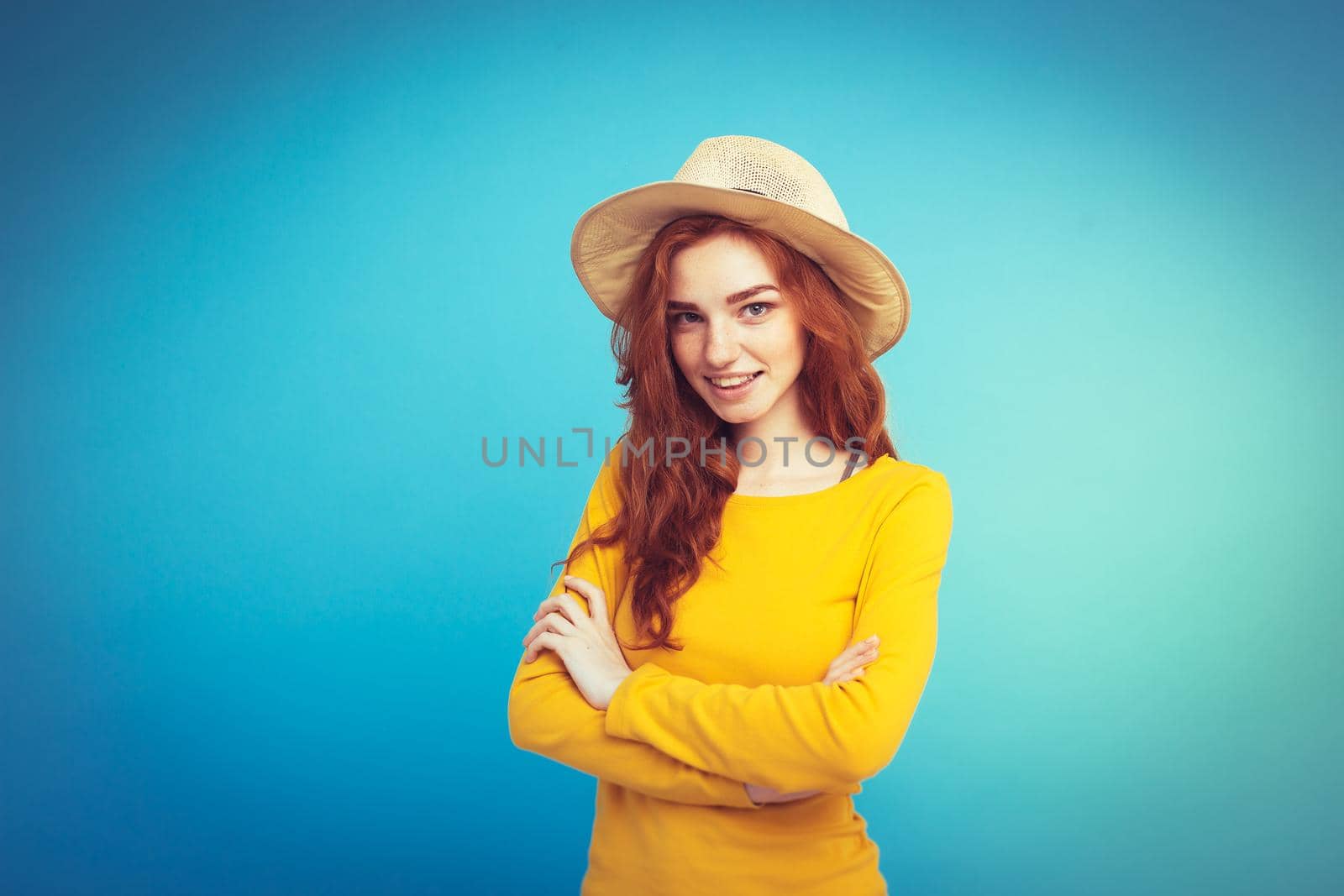 Travel concept - Close up Portrait young beautiful attractive redhair girl wtih trendy hat and sunglass smiling. Blue Pastel Background. Copy space.