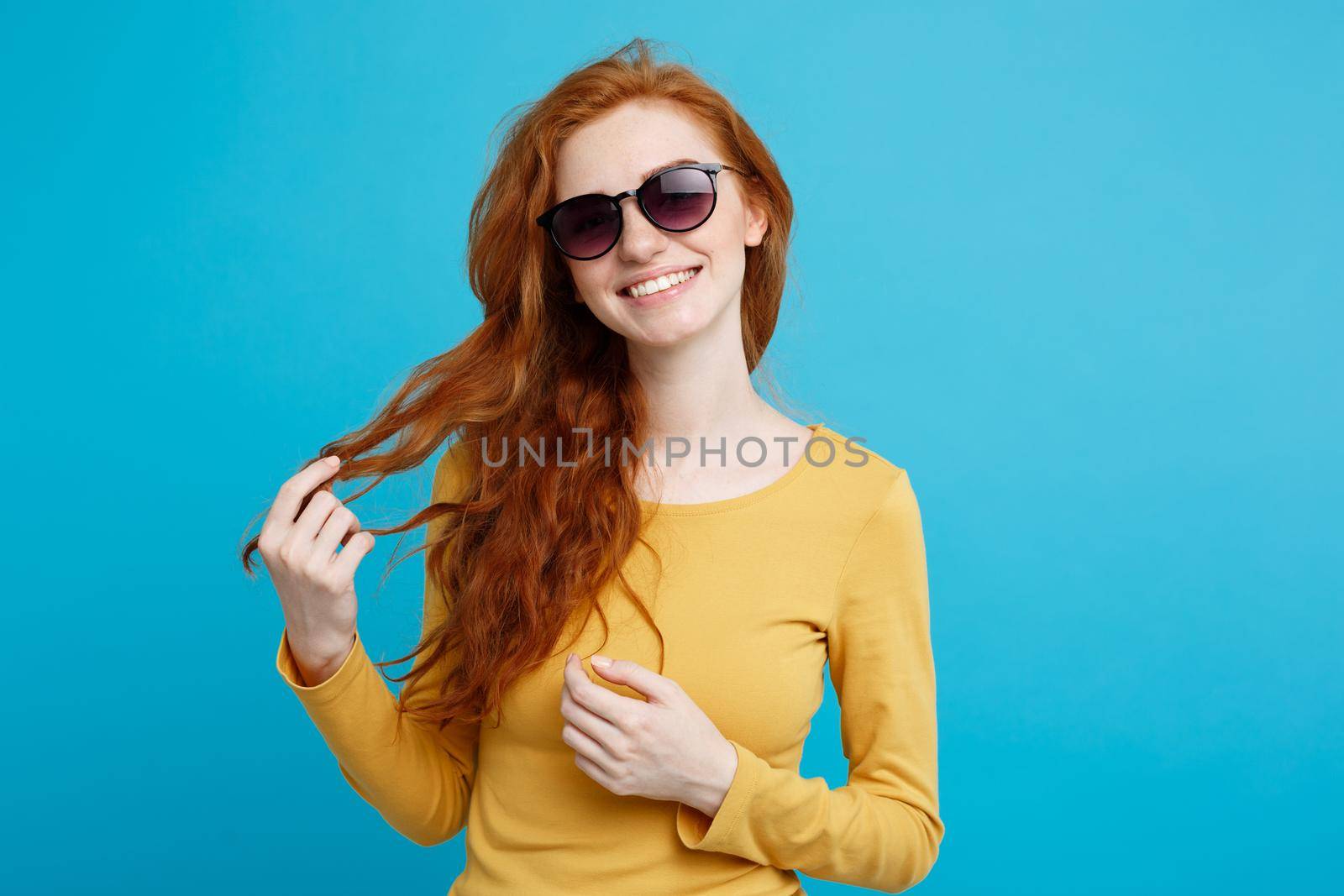 Travel concept - Close up Portrait young beautiful attractive ginger red hair girl with trendy sunglass smiling. Blue Pastel Background. Copy space. by Benzoix