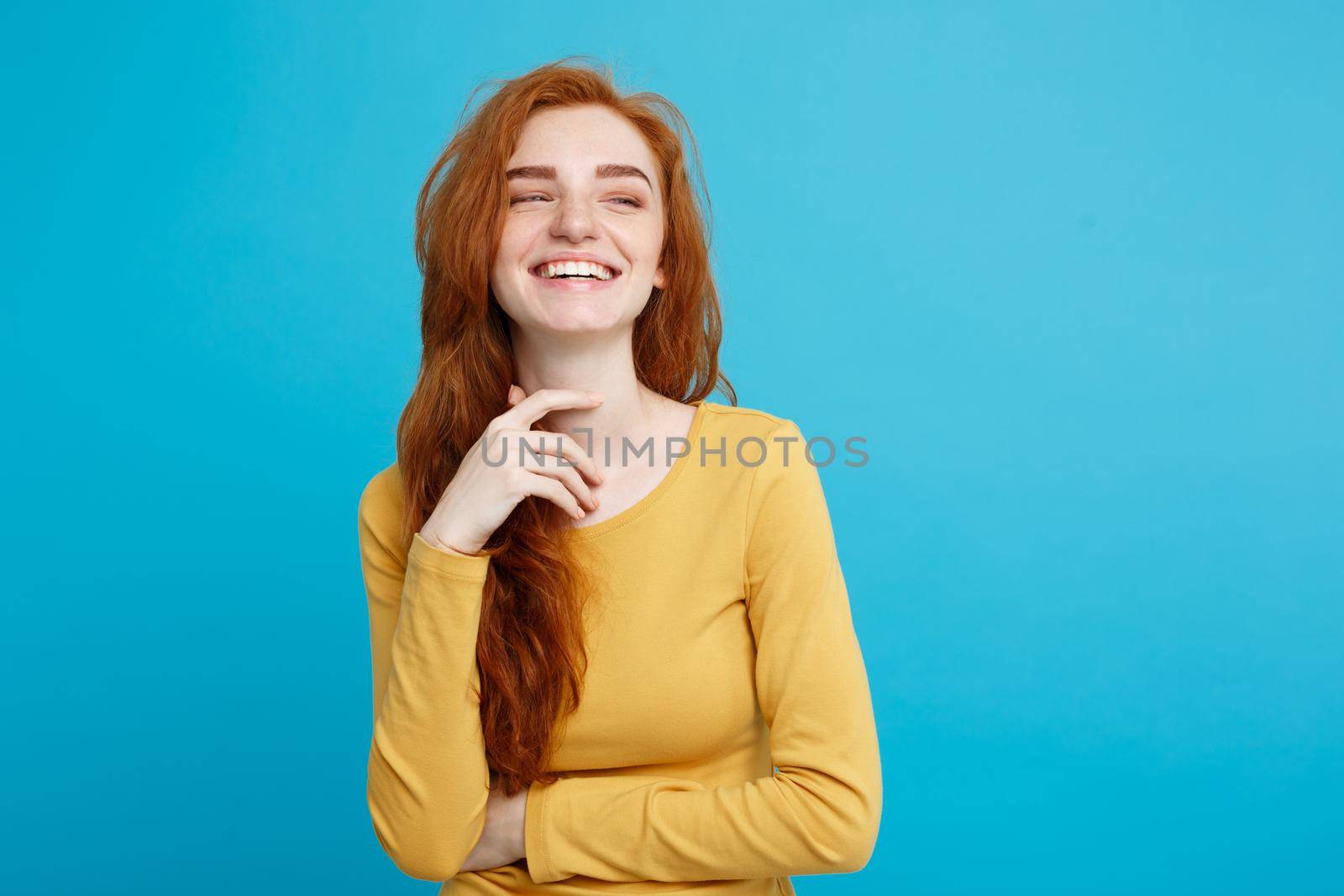 Lifestyle concept - Close up Portrait young beautiful attractive ginger red hair girl playing with her hair with shyness. Blue Pastel Background. Copy space. by Benzoix