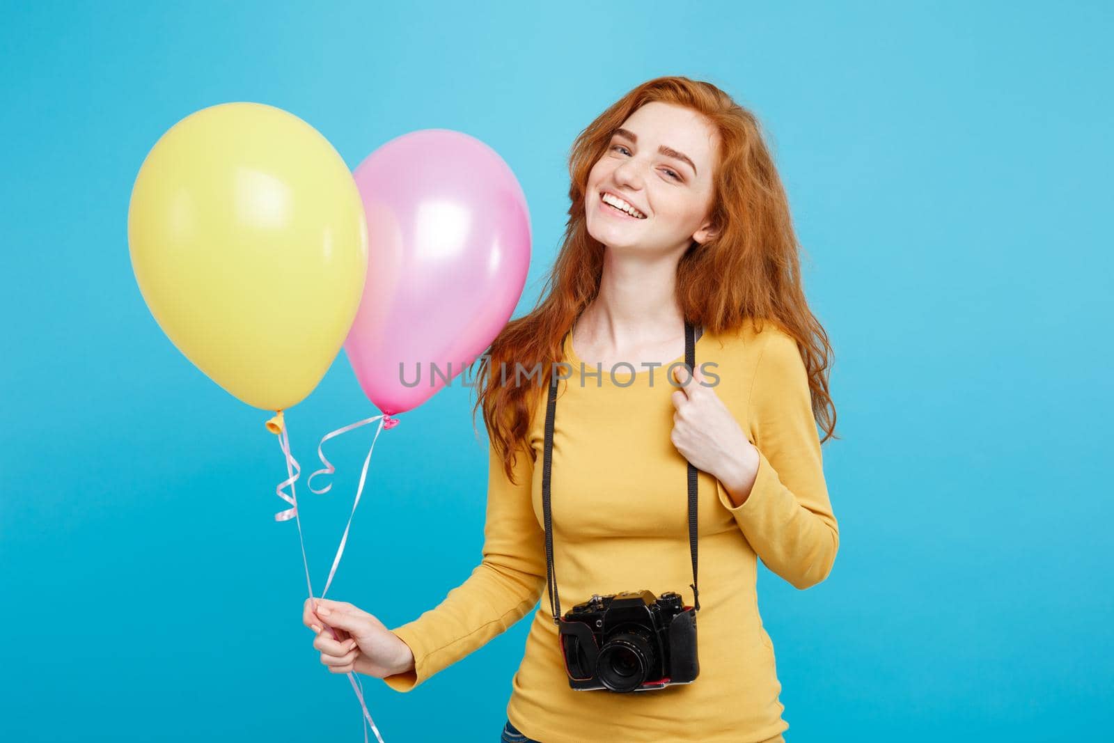 Lifestyle and Party concept - Close up Portrait young beautiful attractive ginger red hair girl with colorful balloon and vintage camera. Blue Pastel Background. Copy space.