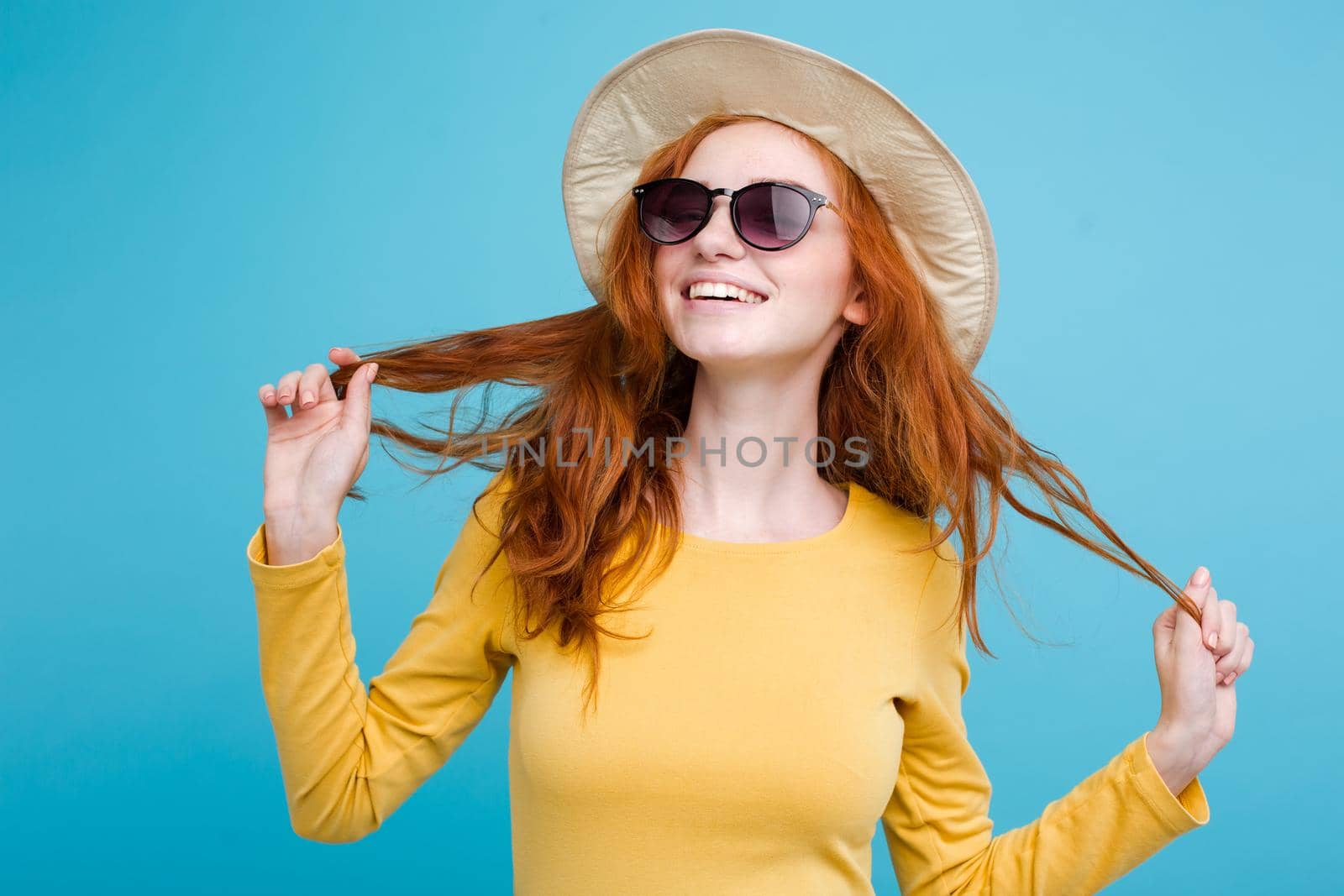 Travel concept - Close up Portrait young beautiful attractive redhair girl wtih trendy hat and sunglass smiling. Blue Pastel Background. Copy space by Benzoix