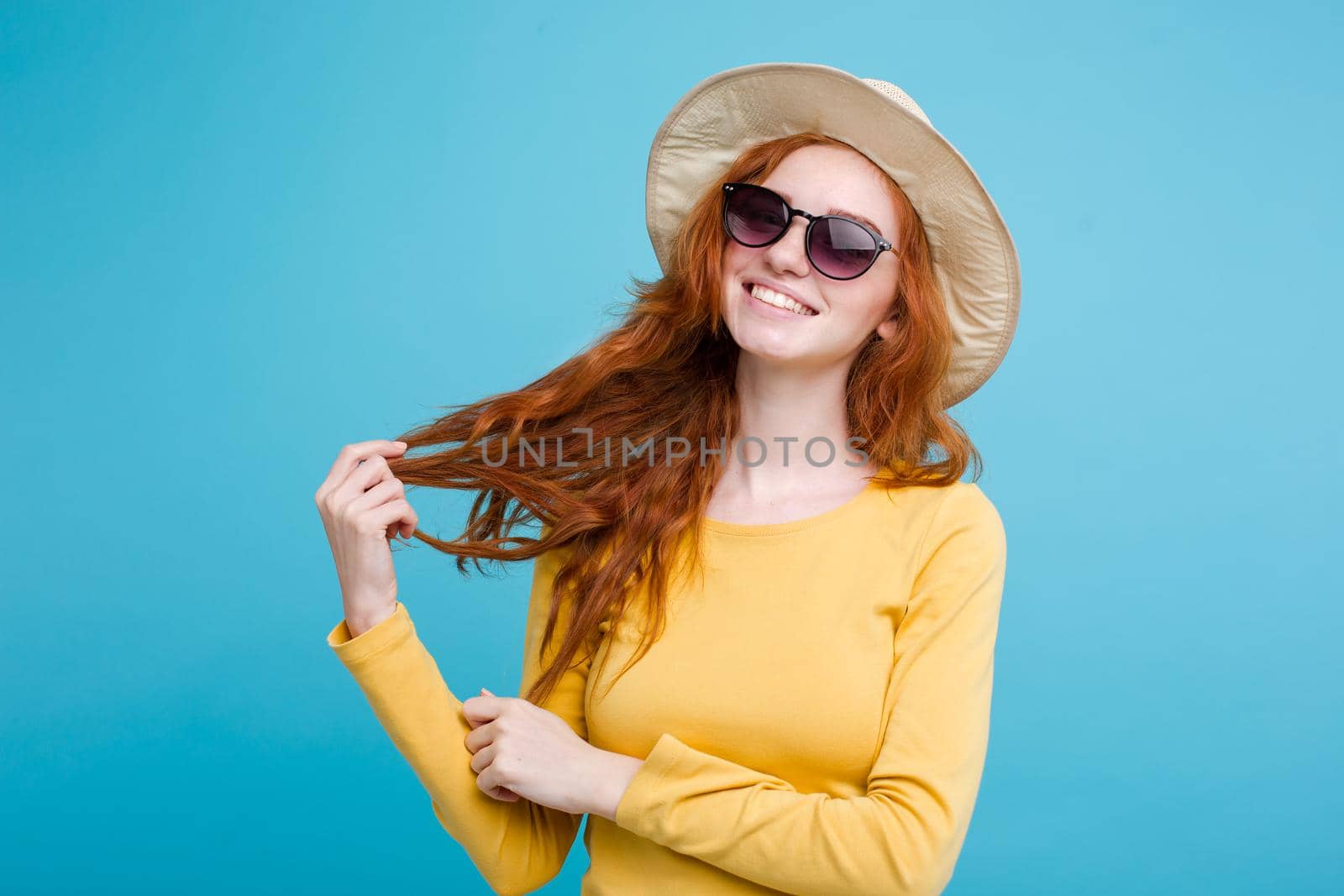 Travel concept - Close up Portrait young beautiful attractive redhair girl wtih trendy hat and sunglass smiling. Blue Pastel Background. Copy space by Benzoix