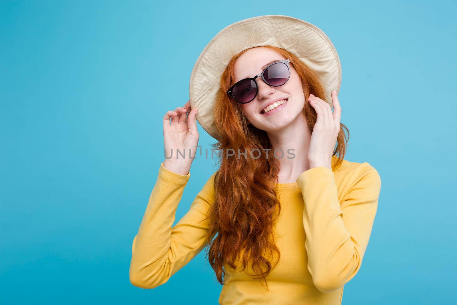 Travel concept - Close up Portrait young beautiful attractive redhair girl wtih trendy hat and sunglass smiling. Blue Pastel Background. Copy space by Benzoix