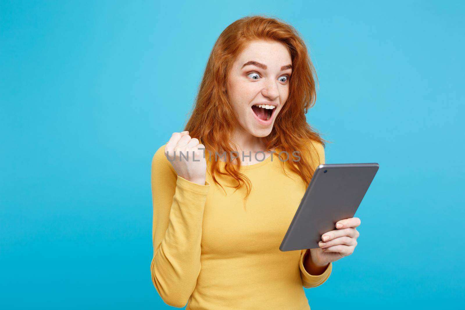 Close up Portrait young beautiful attractive redhair girl happy smiling on digital table with wining something. Blue Pastel Background. Copy space.