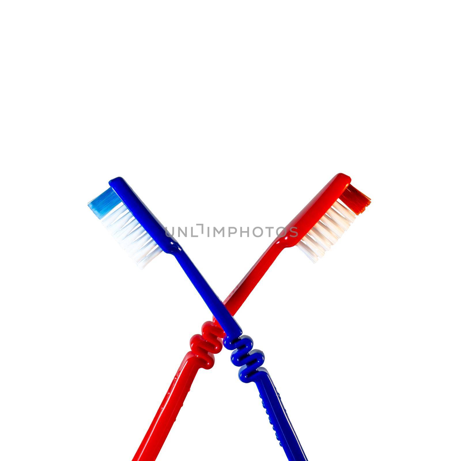 Two toothbrushes crossed on a white background. Blue and red toothbrushes by Puludi