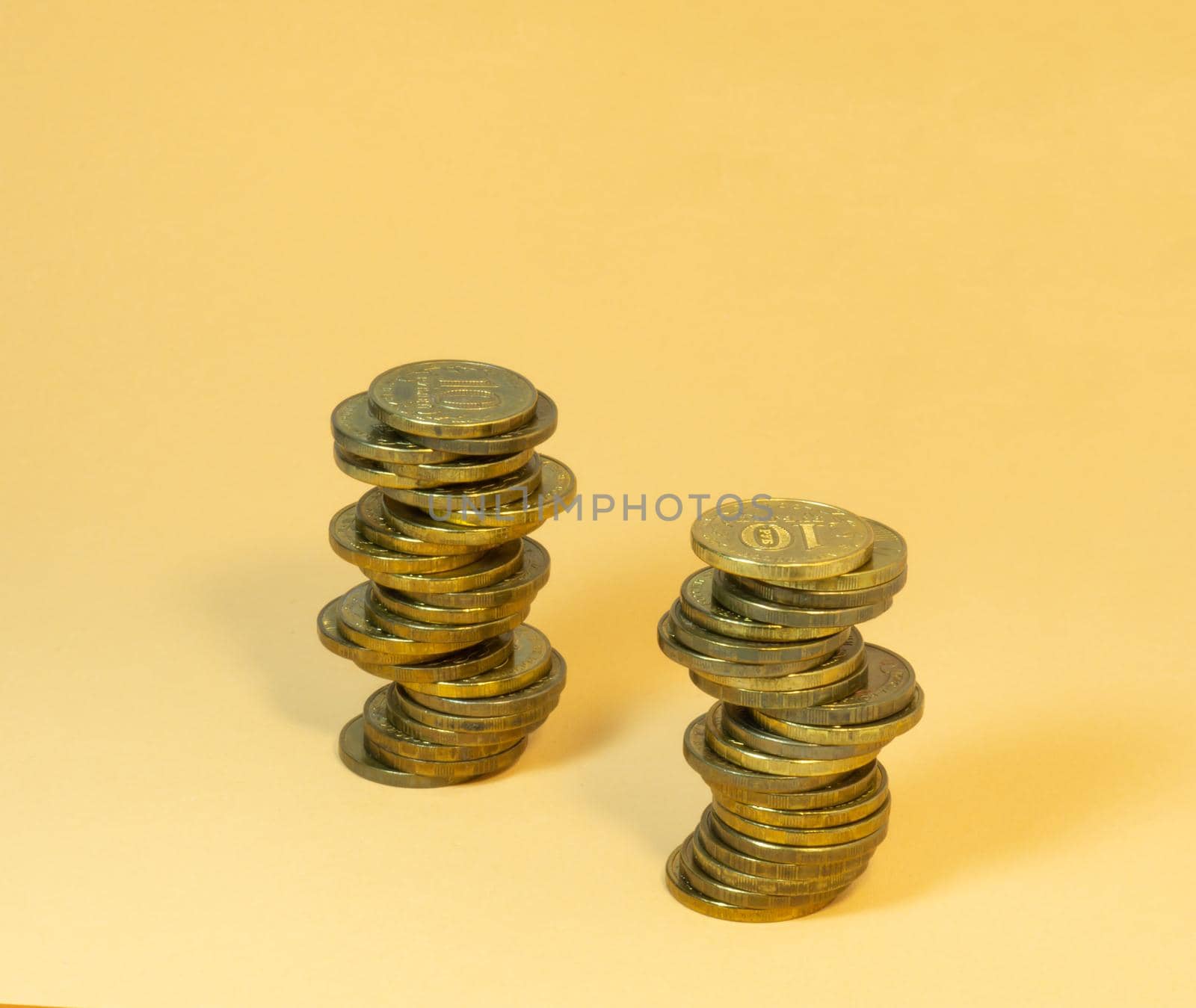 Two turrets made of coins. Money on yellow background by Puludi