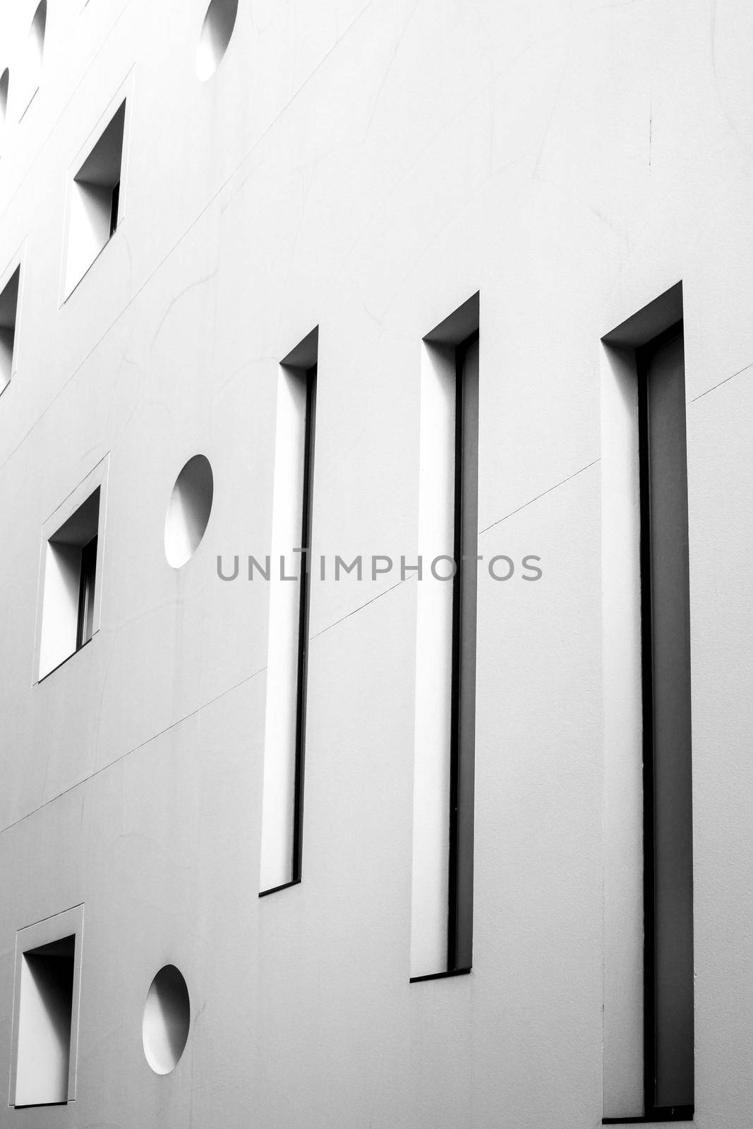 Square and round geometric shaped windows on white stone facade in Spain