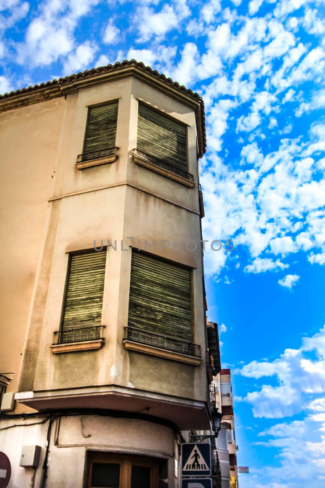 Old facade with wooden green blinds under beautiful sky in Novelda, Alicante, Spain