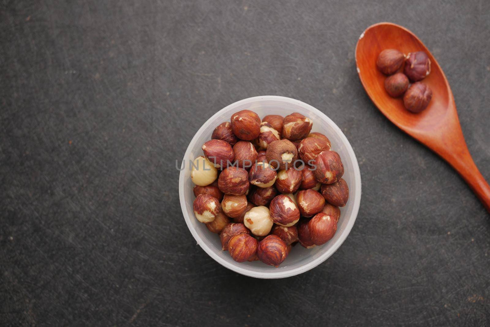 hazelnuts in a container on black background