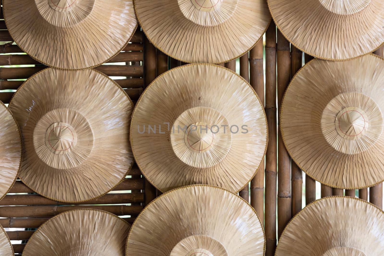 Several farmers' straw hats were hung on a wall made of bamboo. Object and Indigenous culture of Thailand concept.