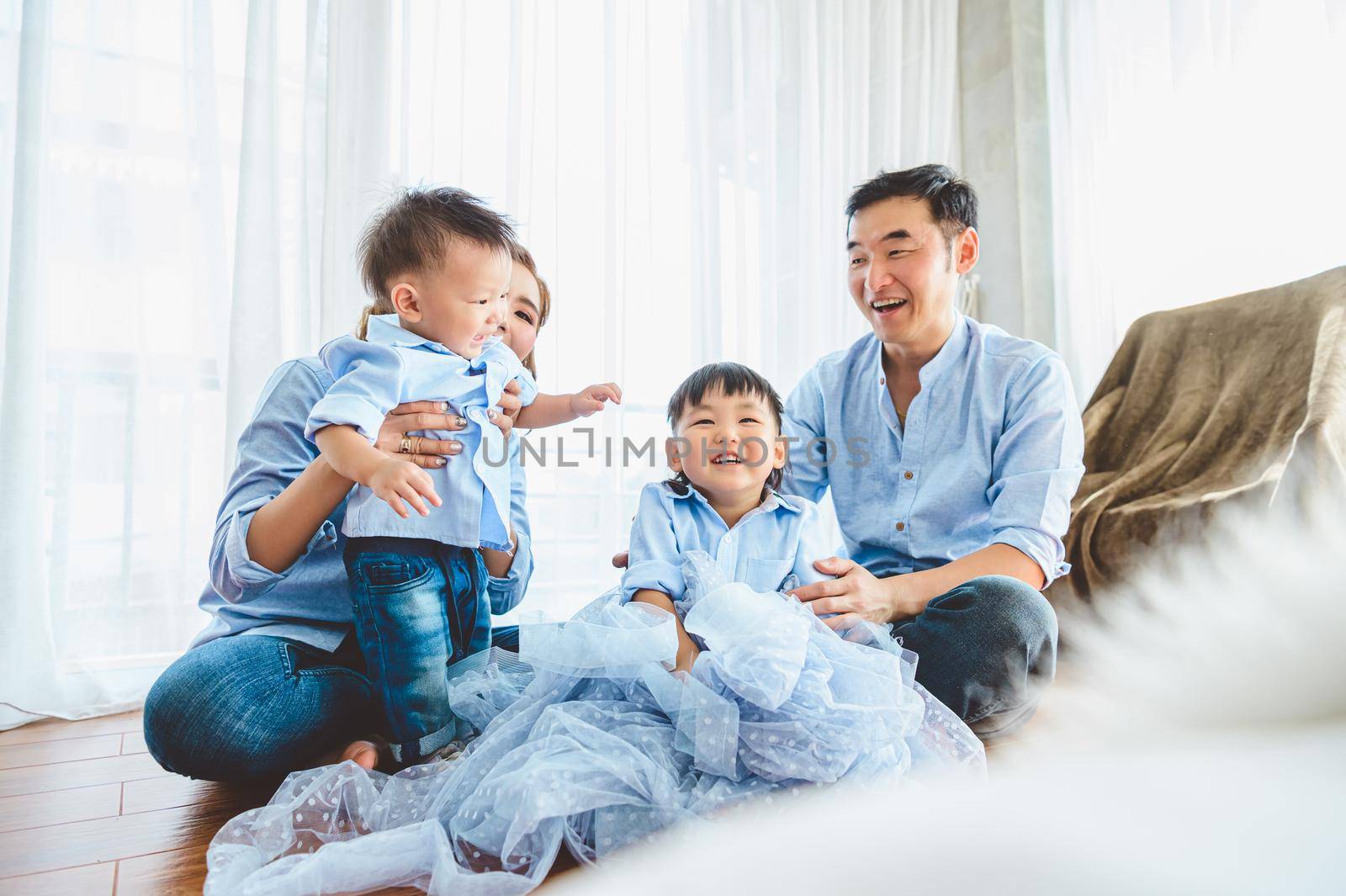 Happy Asian family smile and laugh together in bedroom at home. Two parents and children. People lifestyle in state quarantine after travel on Covid-19 or Coronavirus epidemic concept. Bed foreground