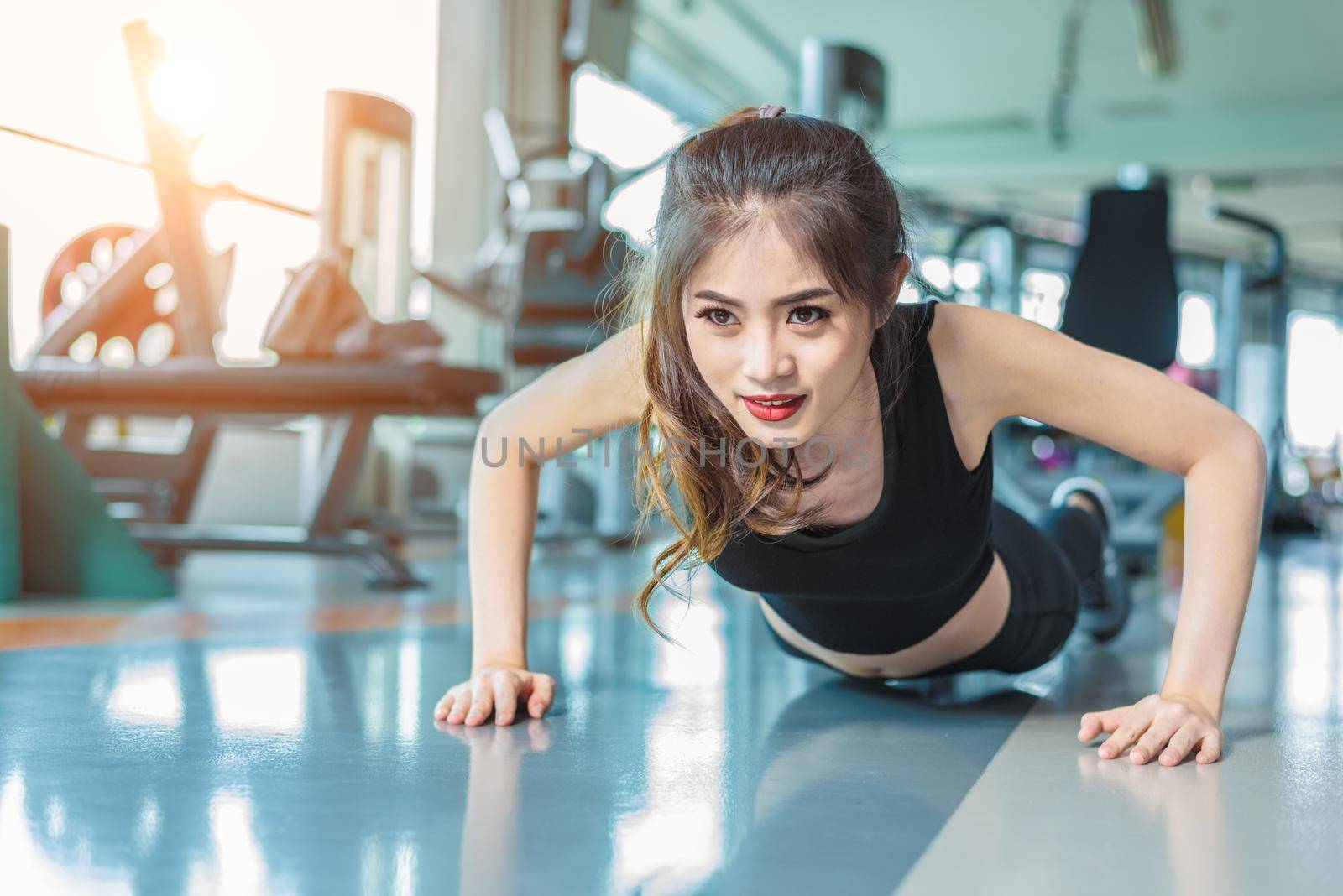 Asian woman fitness girl do pushing ups at fitness gym. Healthcare and Healthy concept. Training and Body build up theme. Strength and Beauty concept