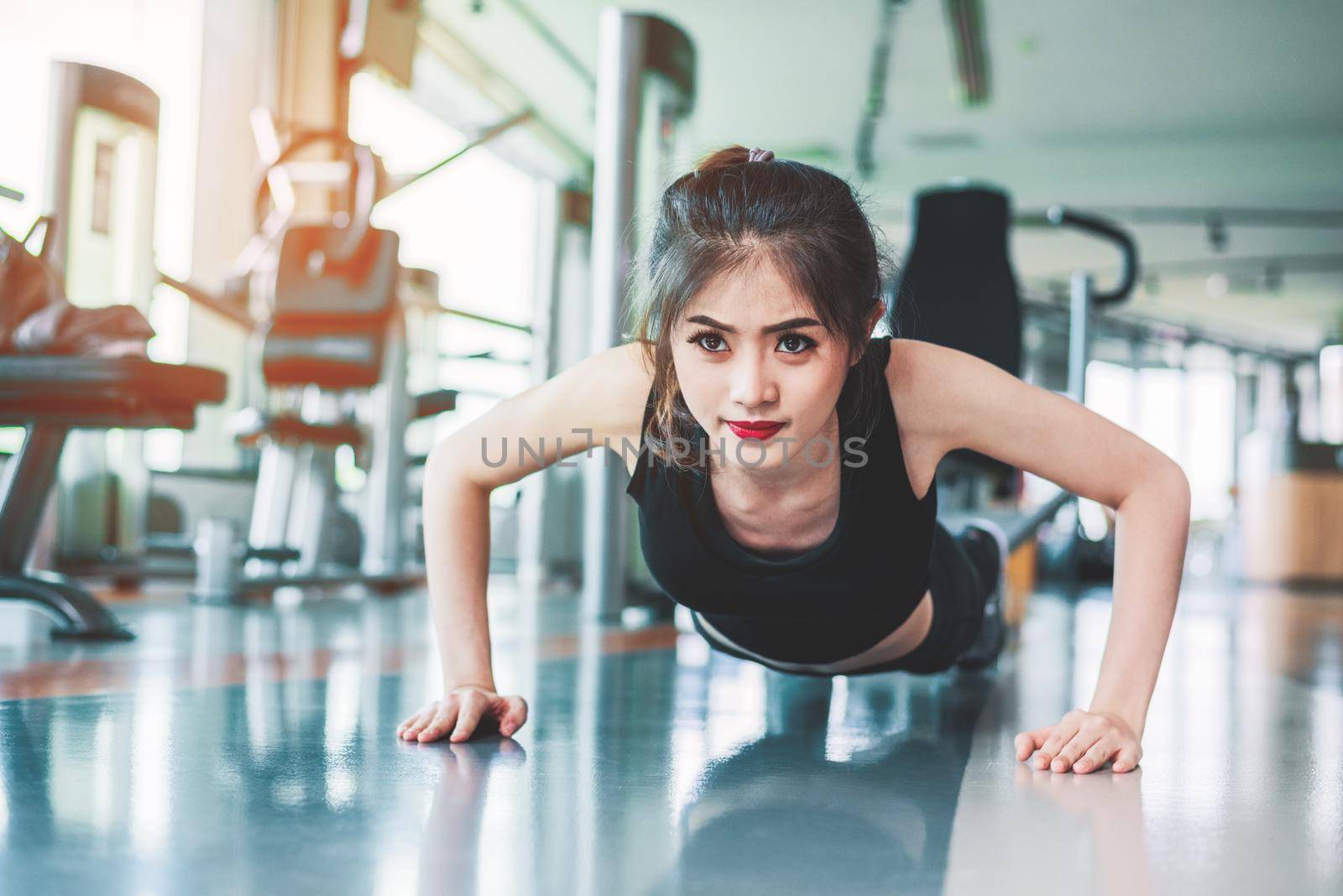 Asian woman fitness girl do pushing ups at fitness gym. Healthcare and Healthy concept. Training and Body build up theme. Strength and Beauty concept