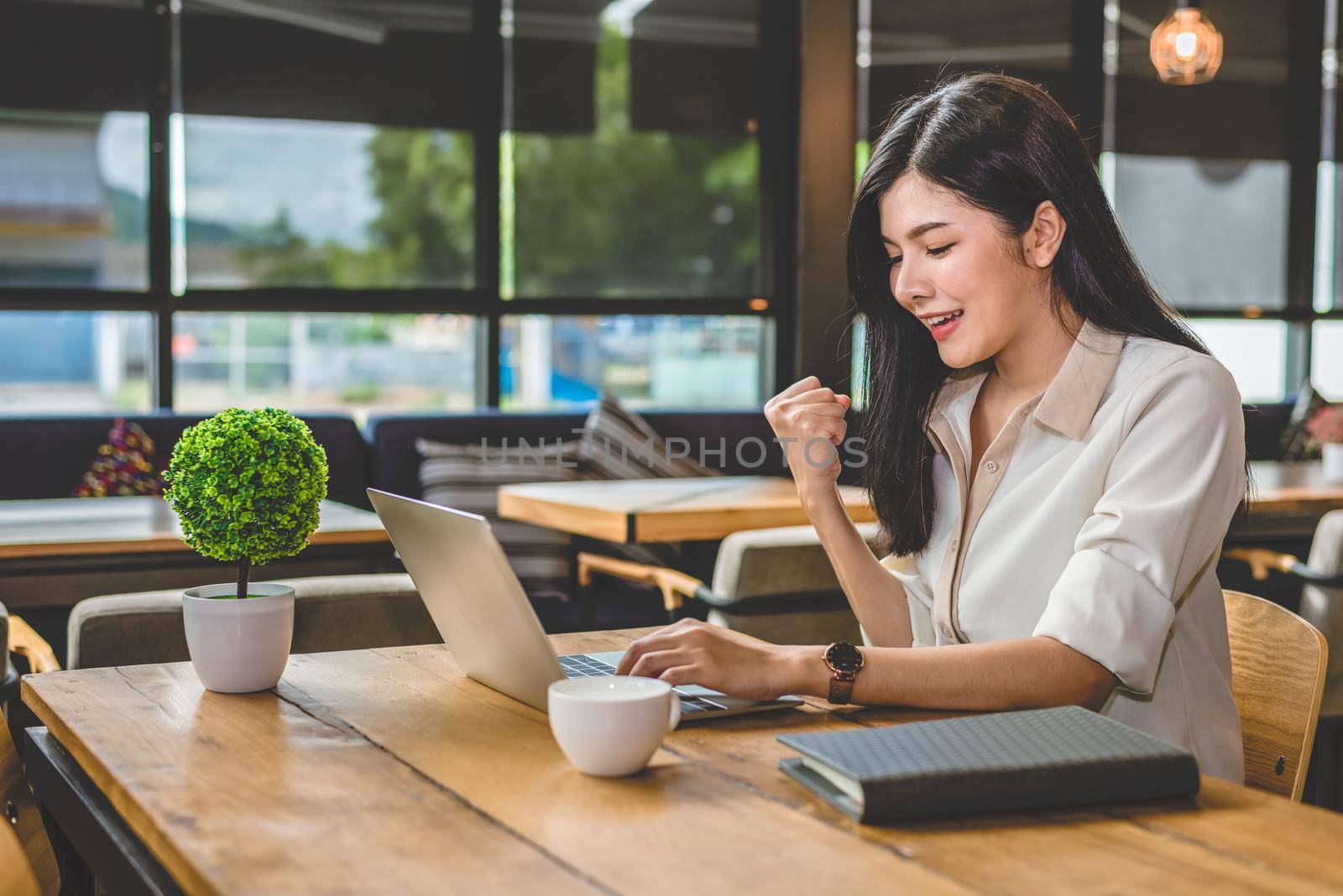 Beauty Asian woman having cheerful gesture after finishing job happily with laptop computer. People and lifestyles concept. Technology and Business working theme. Occupation and coffee shop theme.