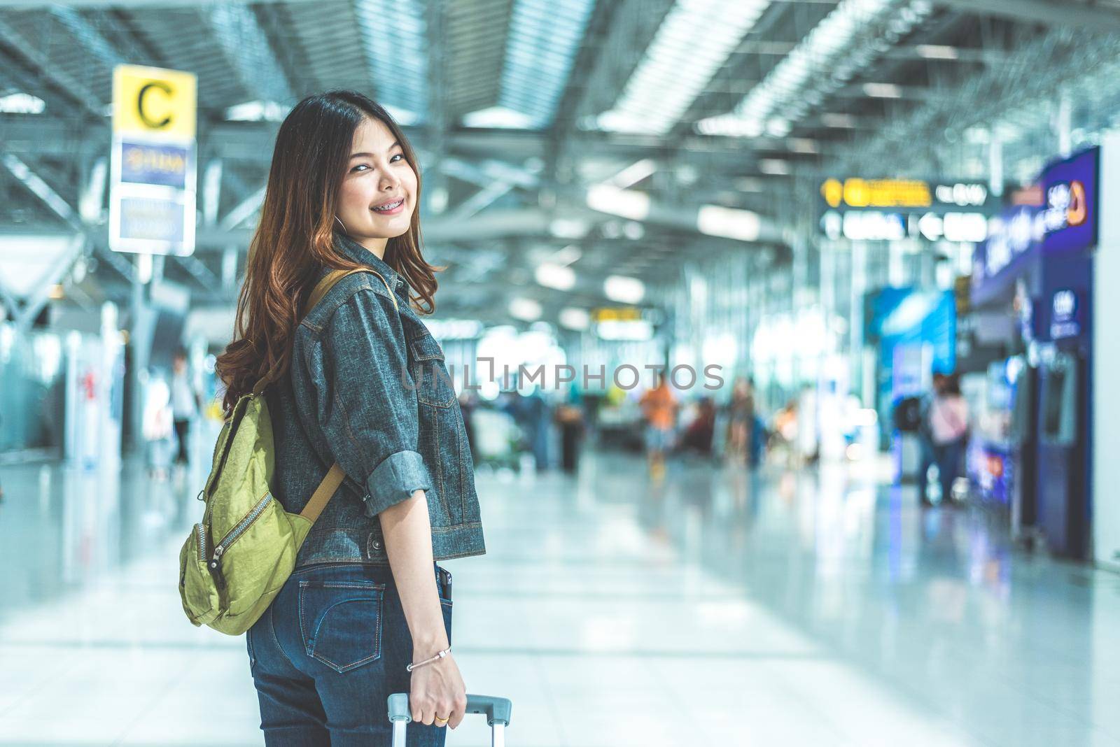 Beauty Asian woman traveling and holding suitcase in the airport. People and Lifestyles concept. Travel around the world theme. Look back portrait. by MiniStocker