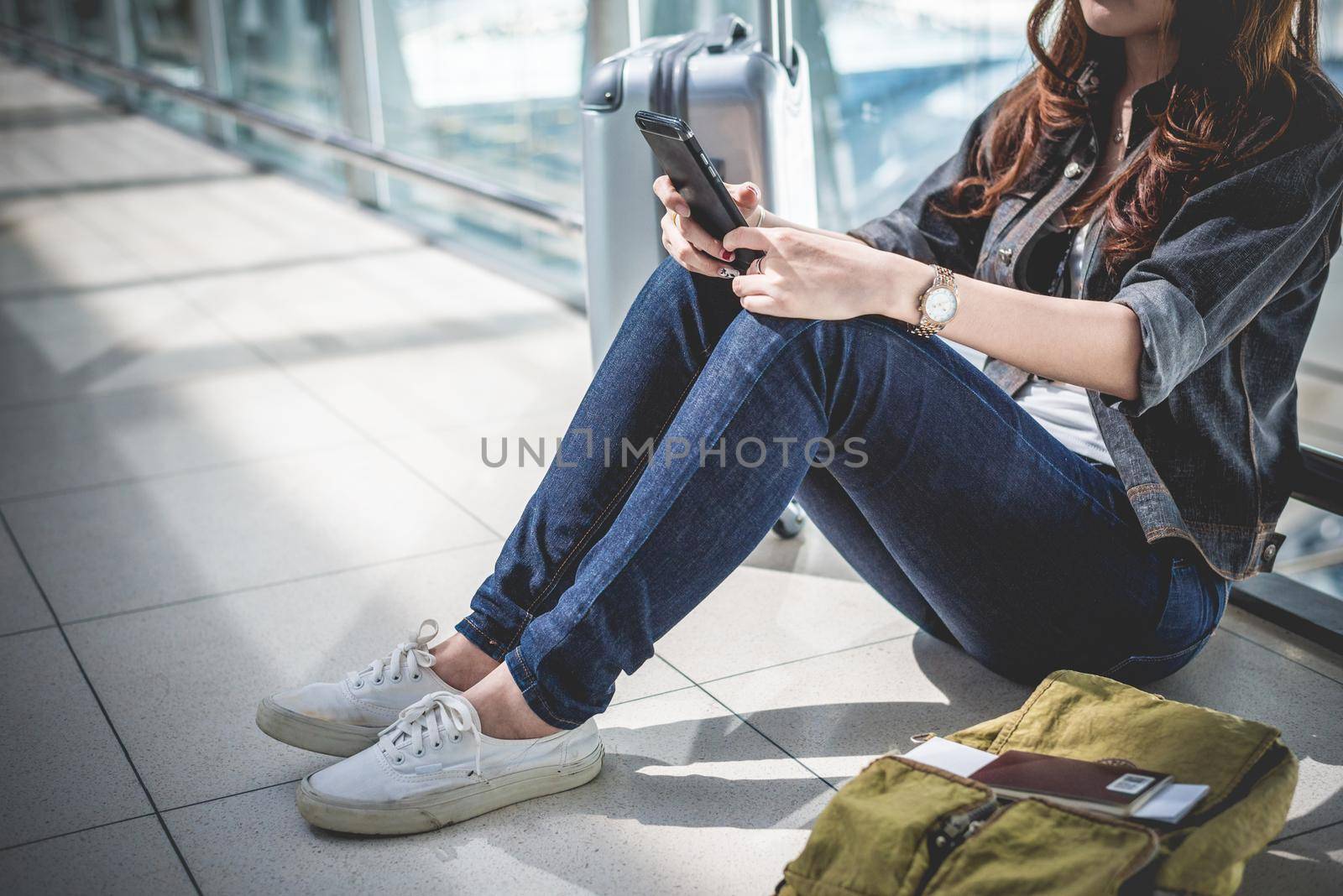 Close up of young woman with bag and suitcase luggage waiting for departure while sitting in airport lounge. Female traveler and tourist theme. High season and vacation concept. Relax and lifestyles by MiniStocker