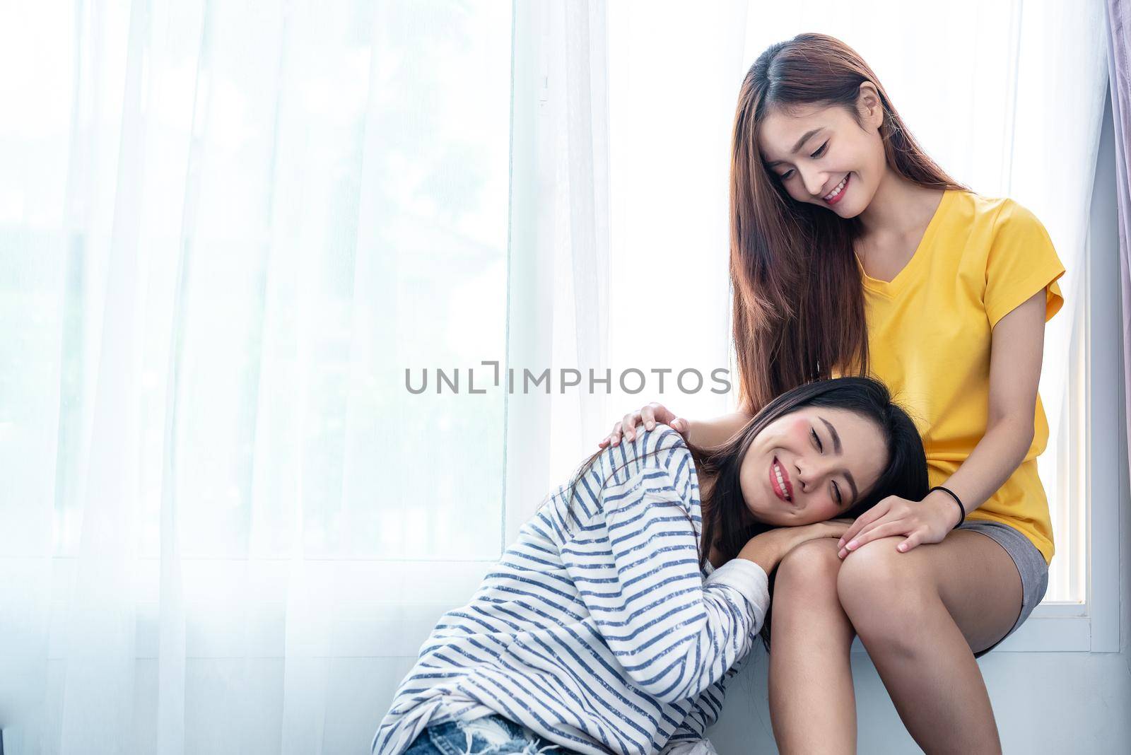Asian couple take care together near white window with soft sunshine in happiness moment together. People and Lifestyles concept. Lesbian and friendships theme. LGBT pride theme.
