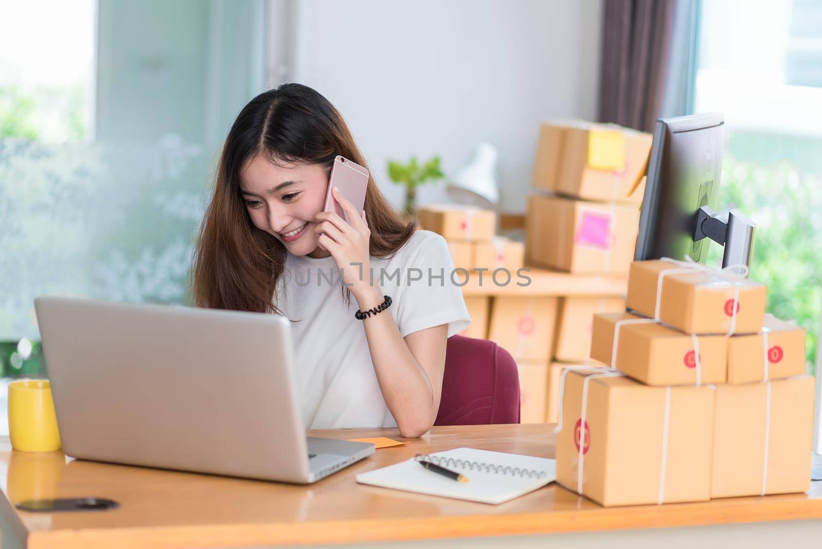 Asian woman enjoy herself while using  internet on laptop and phone in office. Business and marketing and part time concept. Online shopping and business success theme. Happy mood doing working job.