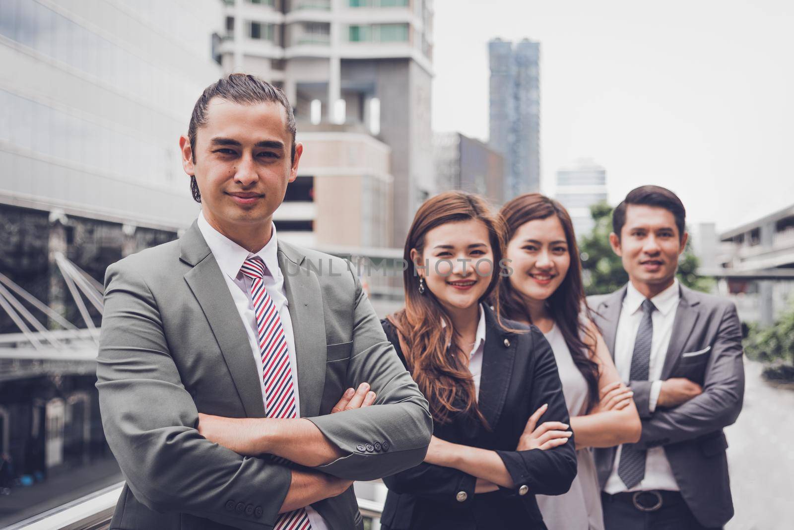 Business people team doing confident gesture portrait at outdoor in city. Multiculturalism of Asian and Caucasian occupation. Happy teamwork business professional leadership in suit. Looking camera