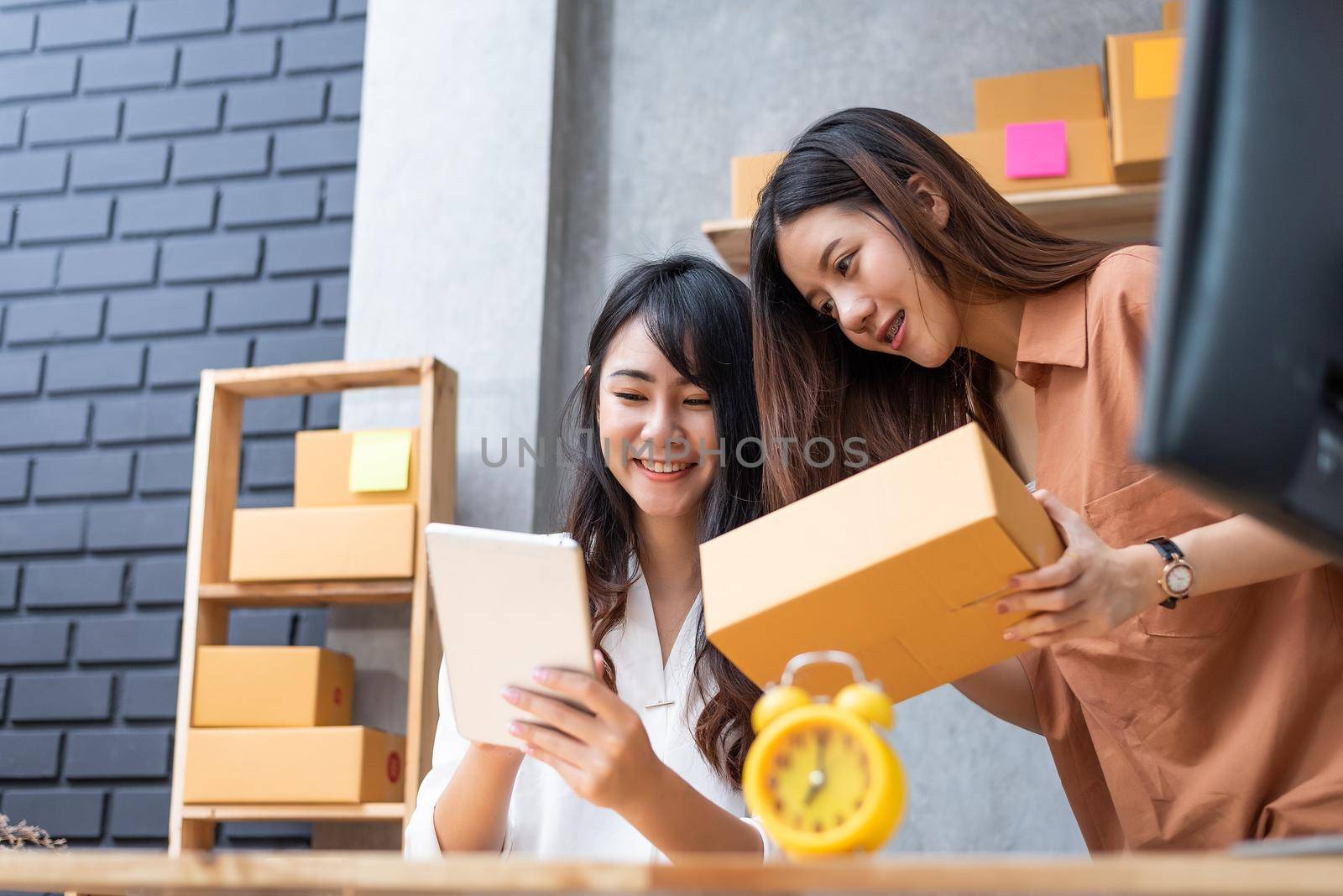 Two young Asian women startup small business entrepreneur SME distribution warehouse with parcel mail box. small  owner home office. Online marketing and product packaging and delivery service