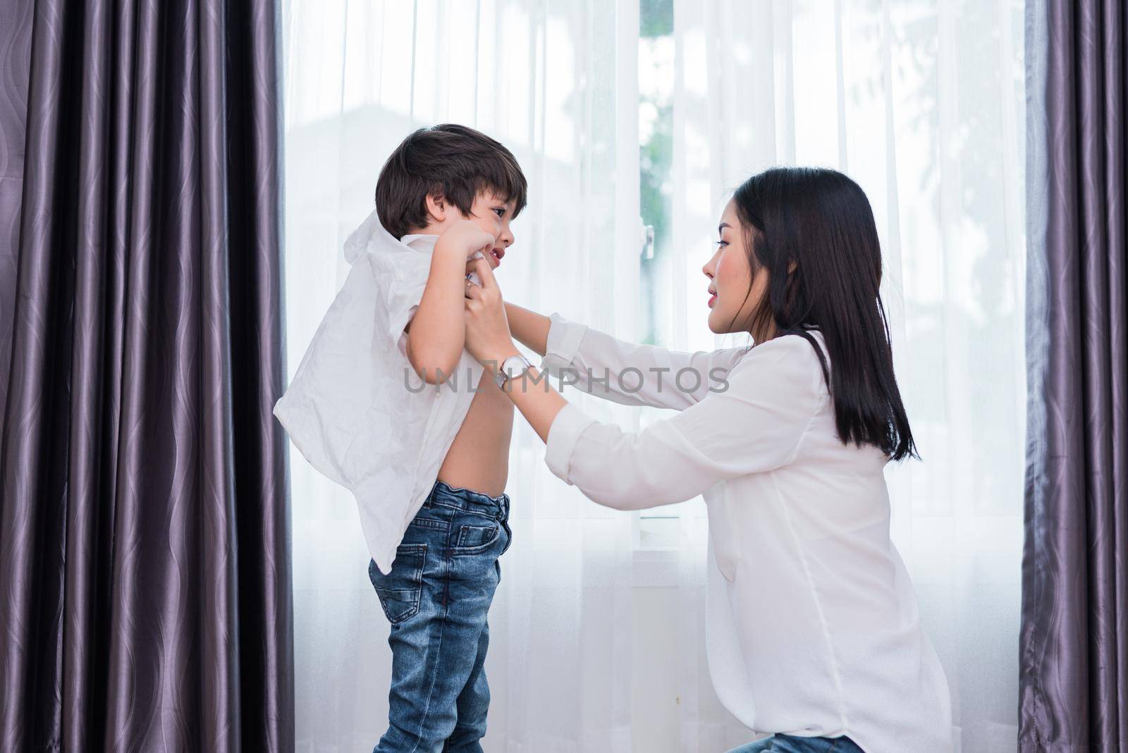 Young Asian mom dressed up son outfits for preparing go to school. Mother and son concept. Happy family and Home sweet home theme. Preschool and Back to school theme.