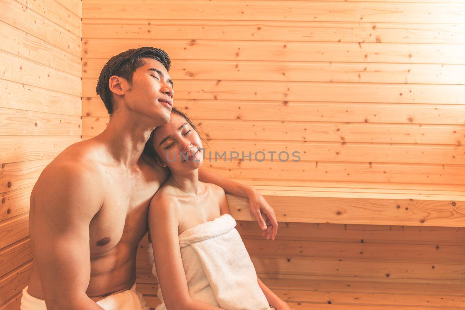 Young Asian couples or lovers have romantic relaxing in sauna room. Skin care heat treatment and body clean up and refreshing in spa with steam bath. Healthy and Honeymoon concept. Happiness together