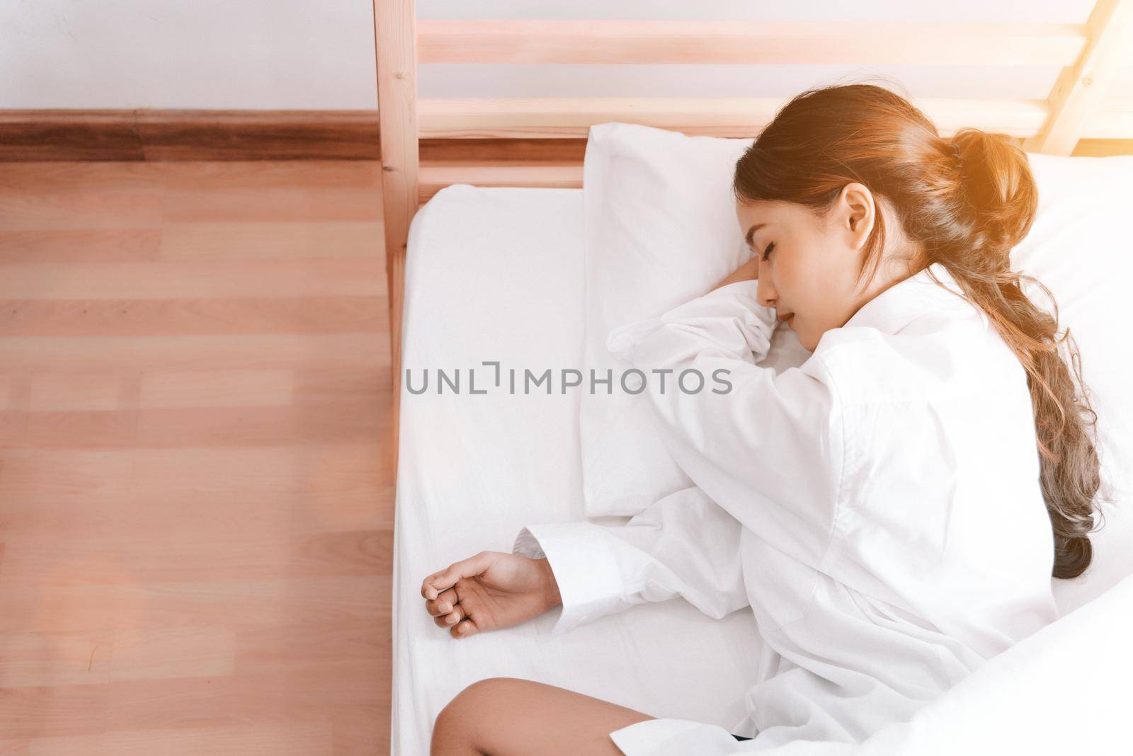 Young Asian woman sleeping on white bed in the morning. Beauty and Holiday concept. Vacation and Relax theme. Interior and People theme. Top view