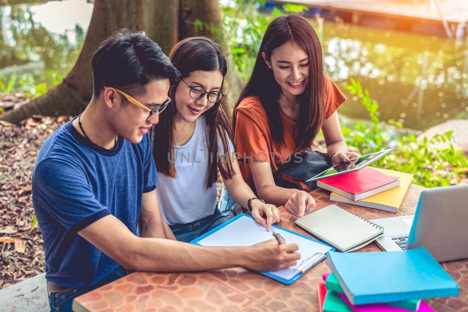 Group of Asian college student reading books and tutoring special class for exam on table at outdoors. Happiness and Education learning concept. Back to school concept. Teen and people theme.